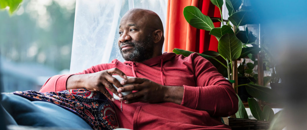 content man holding a coffee cup and looking out a window